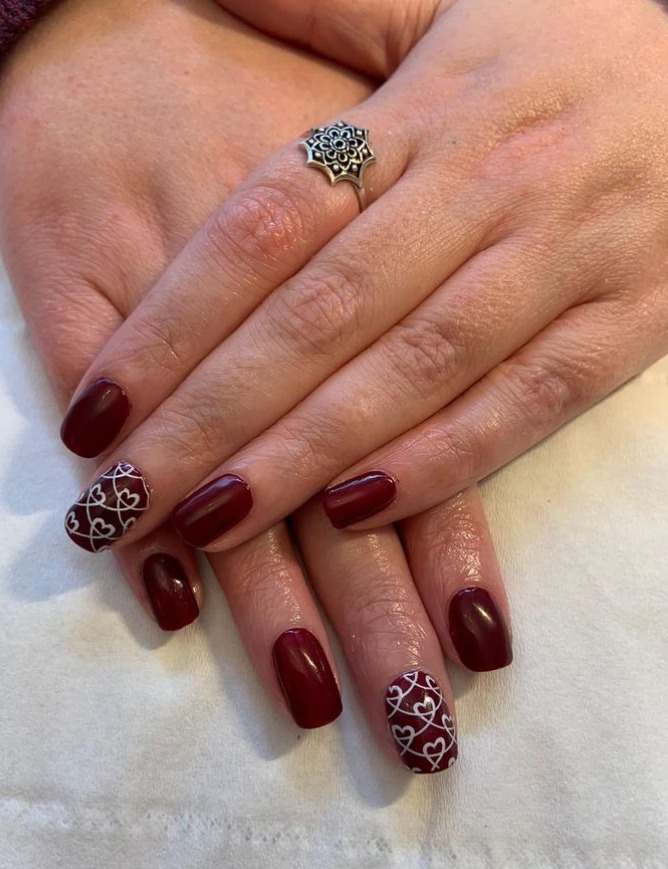 Burgundy gel nails with a heart nail art design