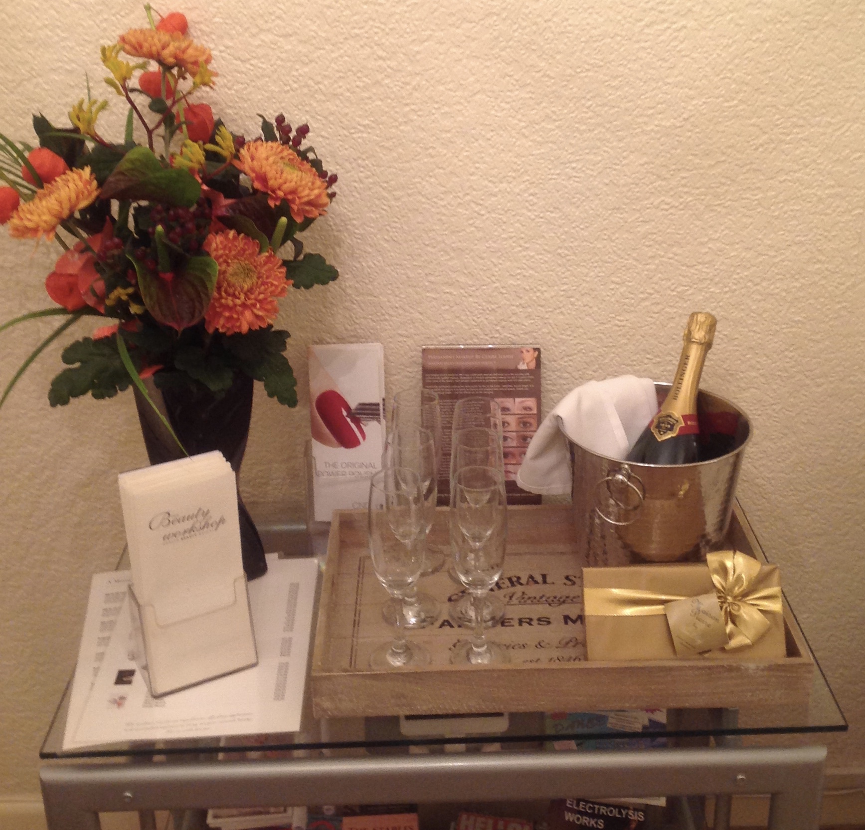 A bridal display of flowers and champagne with a Beauty Workshop card
