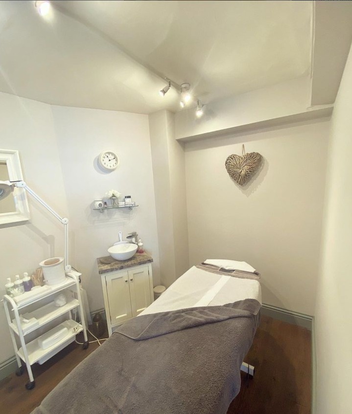 A treatment room with a couch made up with fresh towels and a heart decoration on the wall