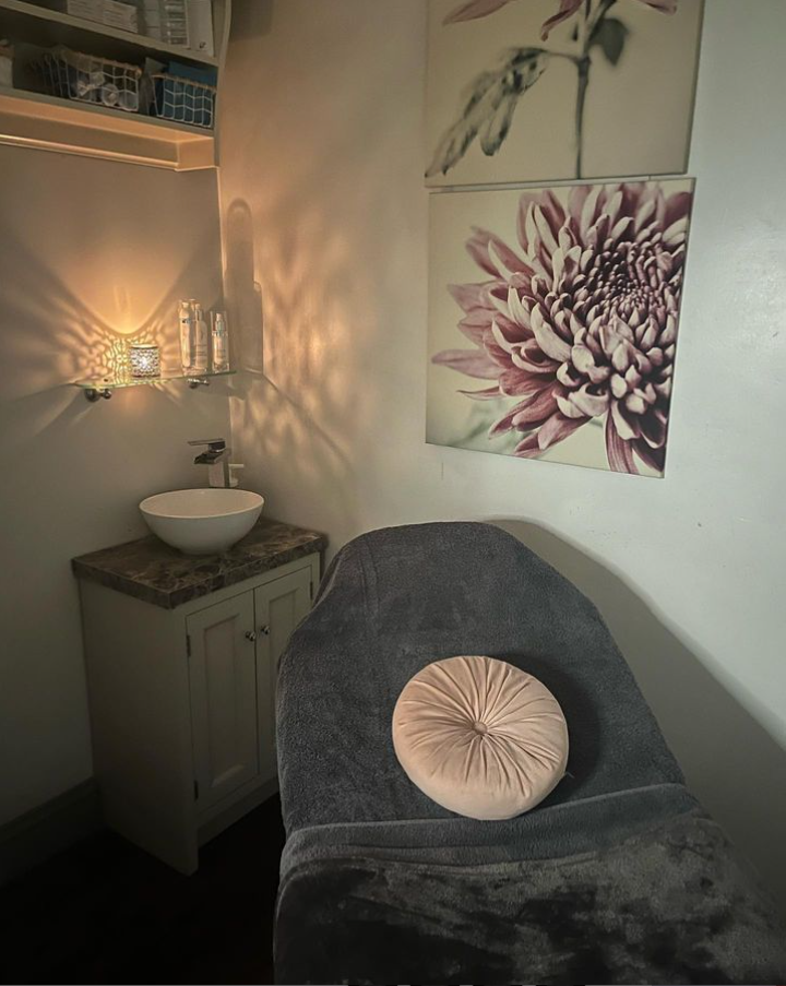 A candle-lit treatment room with flower canvases on the wall