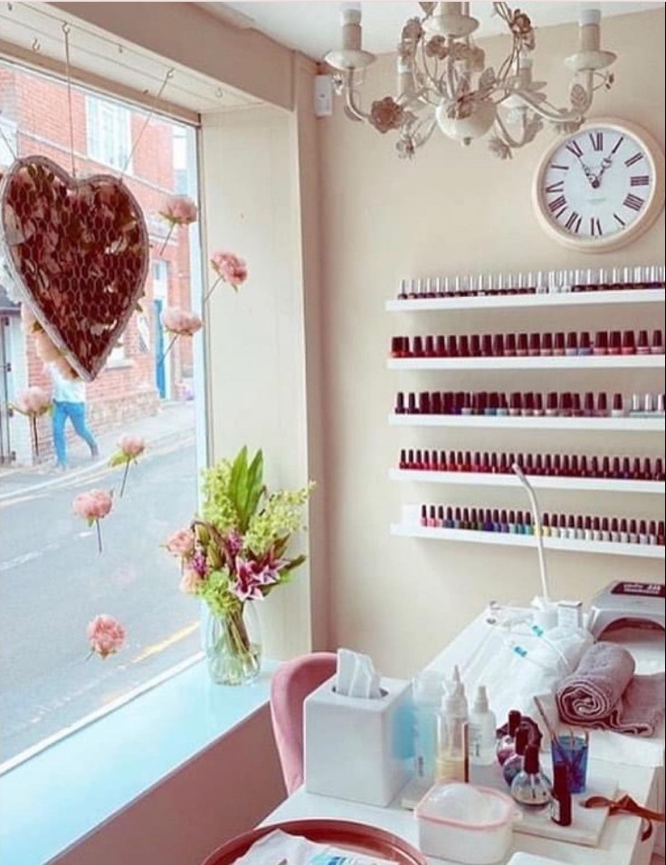 The salon window nail station, with a wall of OPI polishes, a chandelier and a clock
